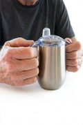 Person holding a stainless steel two-handle drinking cup on a white background