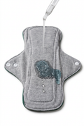 Grey reusable underwear pad with snap fasteners and a liquid demonstration on a white background